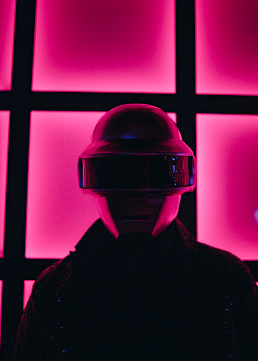 a person wearing a helmet standing in front of a wall of pink squares